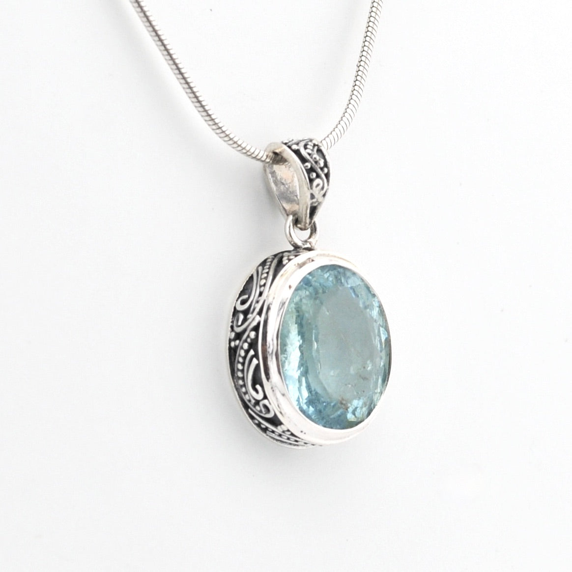 Silver pendant with a blue gemstone on a white background
