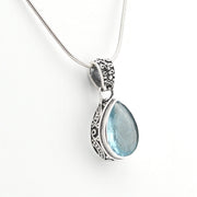 Silver pendant with a blue teardrop-shaped gemstone on a white background