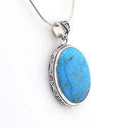 Blue stone pendant on a silver chain against a white background