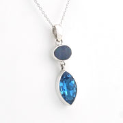 A silver pendant necklace featuring a marquise-cut blue gemstone and a smaller oval dark blue stone, displayed on a clean white background.