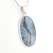 Oval-shaped blue stone pendant on a silver chain against a white background