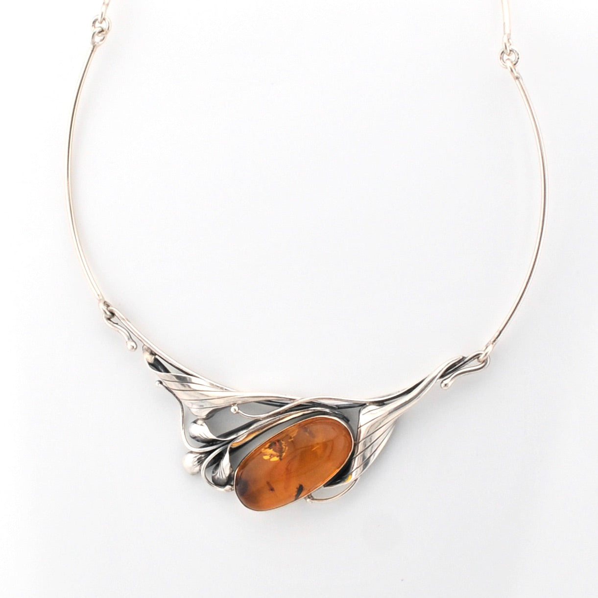 Silver necklace with a large amber stone on a white background