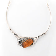 Silver necklace with a large amber stone on a white background