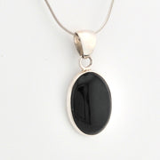 Black pendant on a silver chain against a white background