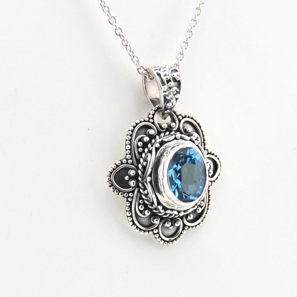 Silver pendant with blue gemstone on a white background