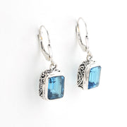 Silver earrings with blue gemstones on a white background