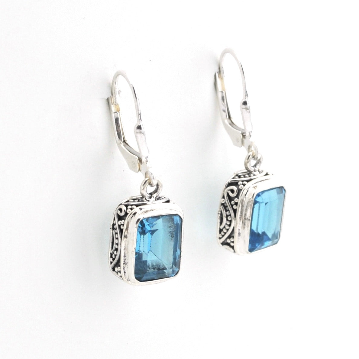 Silver earrings with blue gemstones on a white background