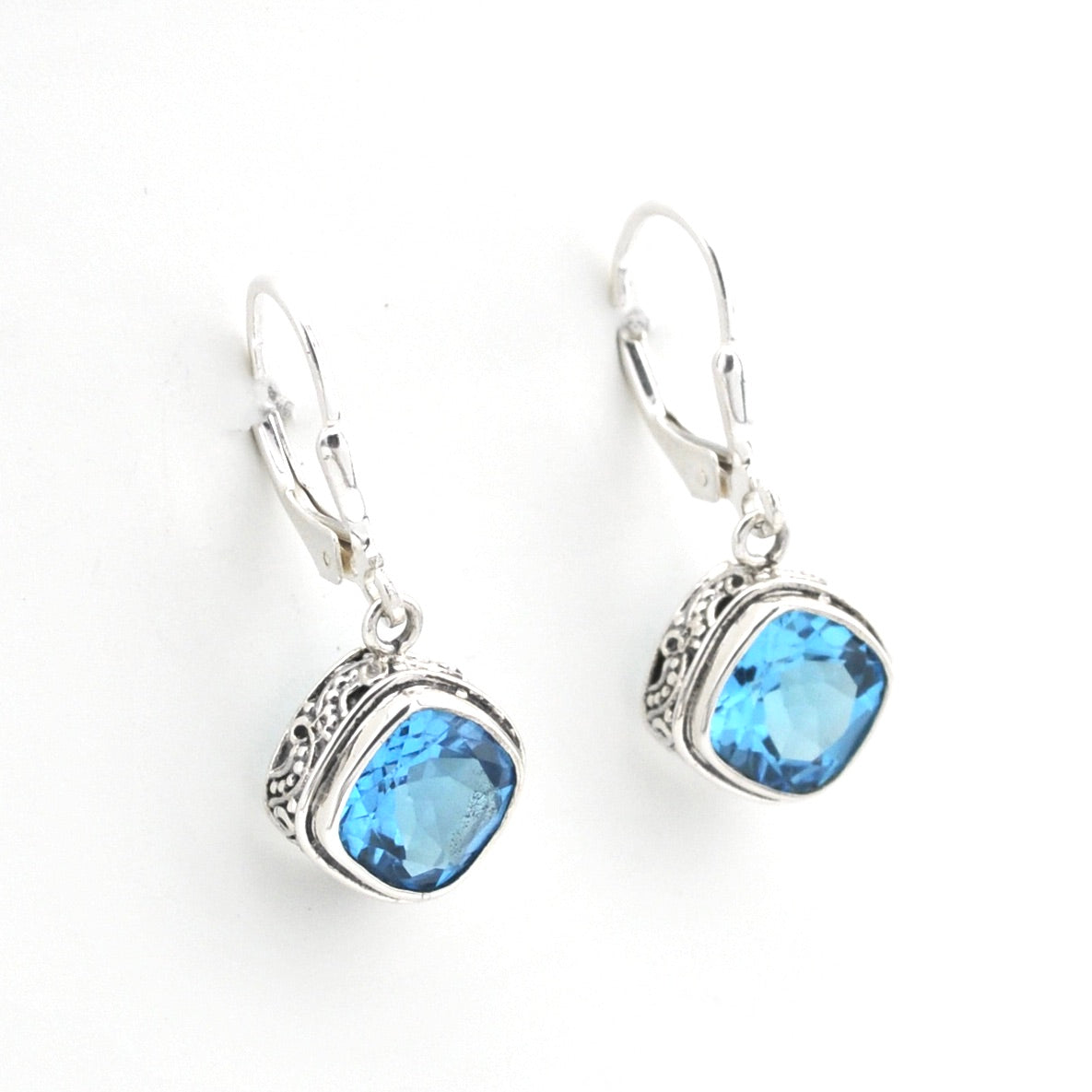 Pair of silver earrings with blue gemstones on a white background