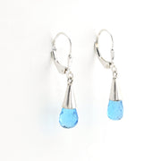 Pair of earrings with blue teardrop beads and silver hooks on a white background