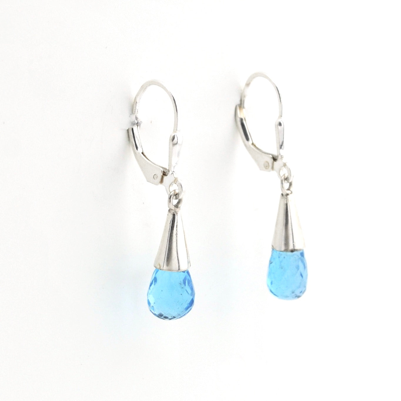 Pair of earrings with blue teardrop beads and silver hooks on a white background