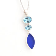 Necklace with blue gemstones and a blue sea glass pendant on a white background