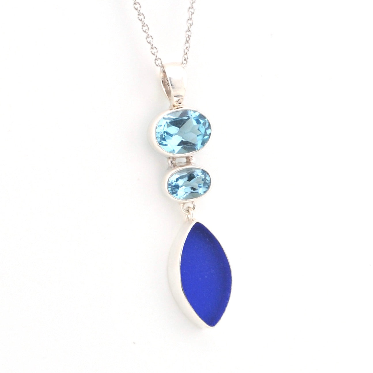 Necklace with blue gemstones and a blue sea glass pendant on a white background