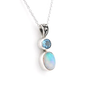 A silver pendant necklace featuring a stacked gemstone design with a small round light blue stone and a larger oval iridescent opal stone, suspended from a delicate silver chain on a white background.
