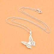 Silver butterfly pendant necklace on a beige background