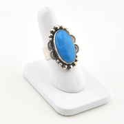 Blue stone ring with silver band on a white stand
