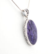 Purple oval pendant with silver frame on a white background