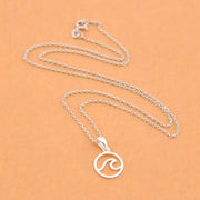 Silver necklace with a wave pendant on a beige background