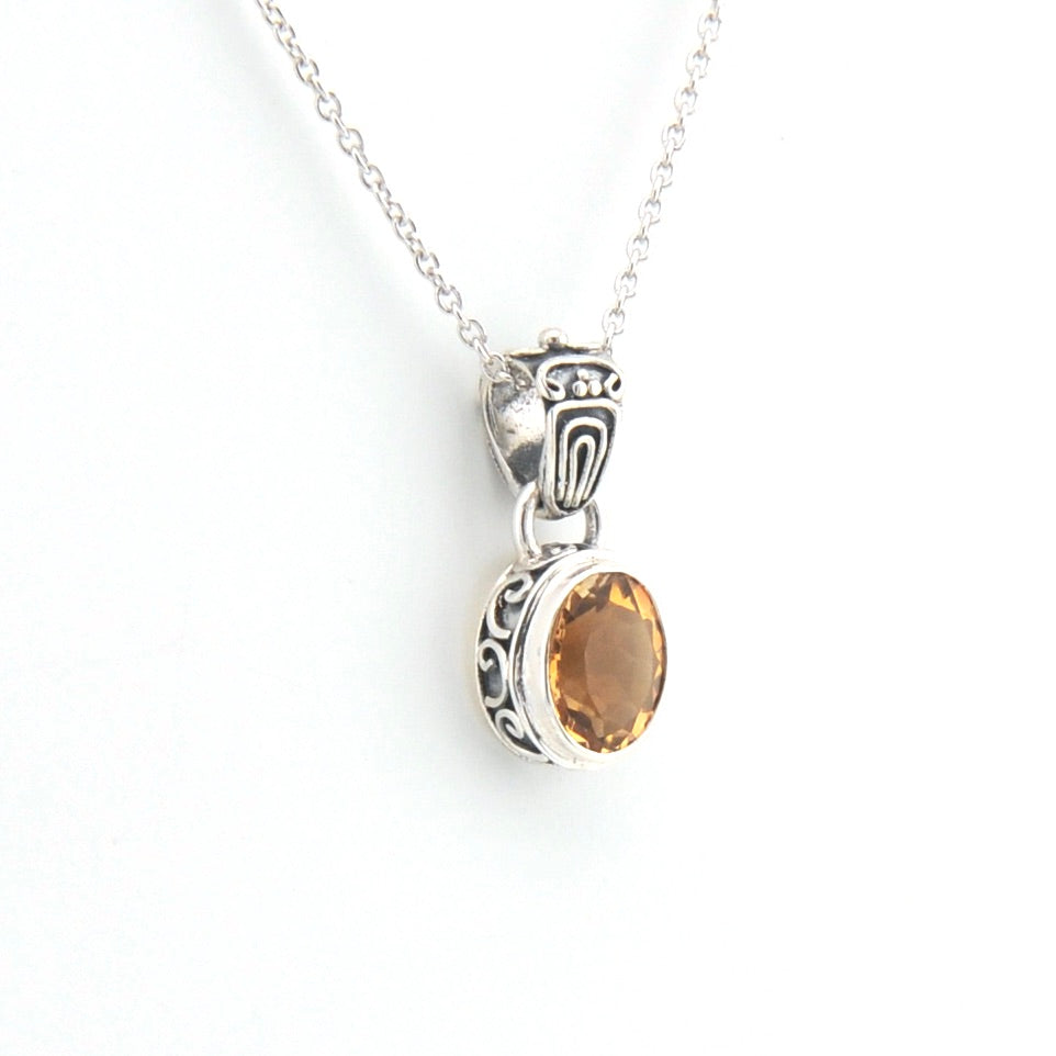 Silver pendant with a yellow gemstone on a white background