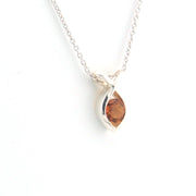 Silver necklace with a marquise-shaped amber pendant on a white background