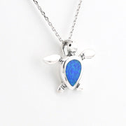 Silver turtle pendant with blue stone on a white background