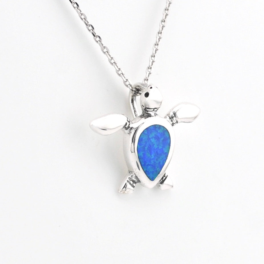 Silver turtle pendant with blue stone on a white background
