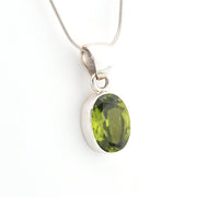 Green gemstone pendant on a silver chain against a white background