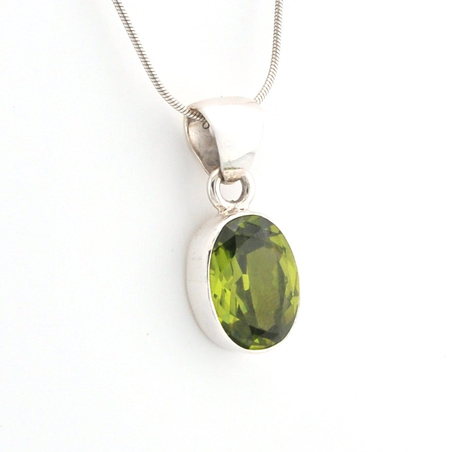 Green gemstone pendant on a silver chain against a white background