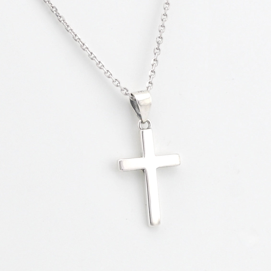 Silver cross pendant on a chain against a white background