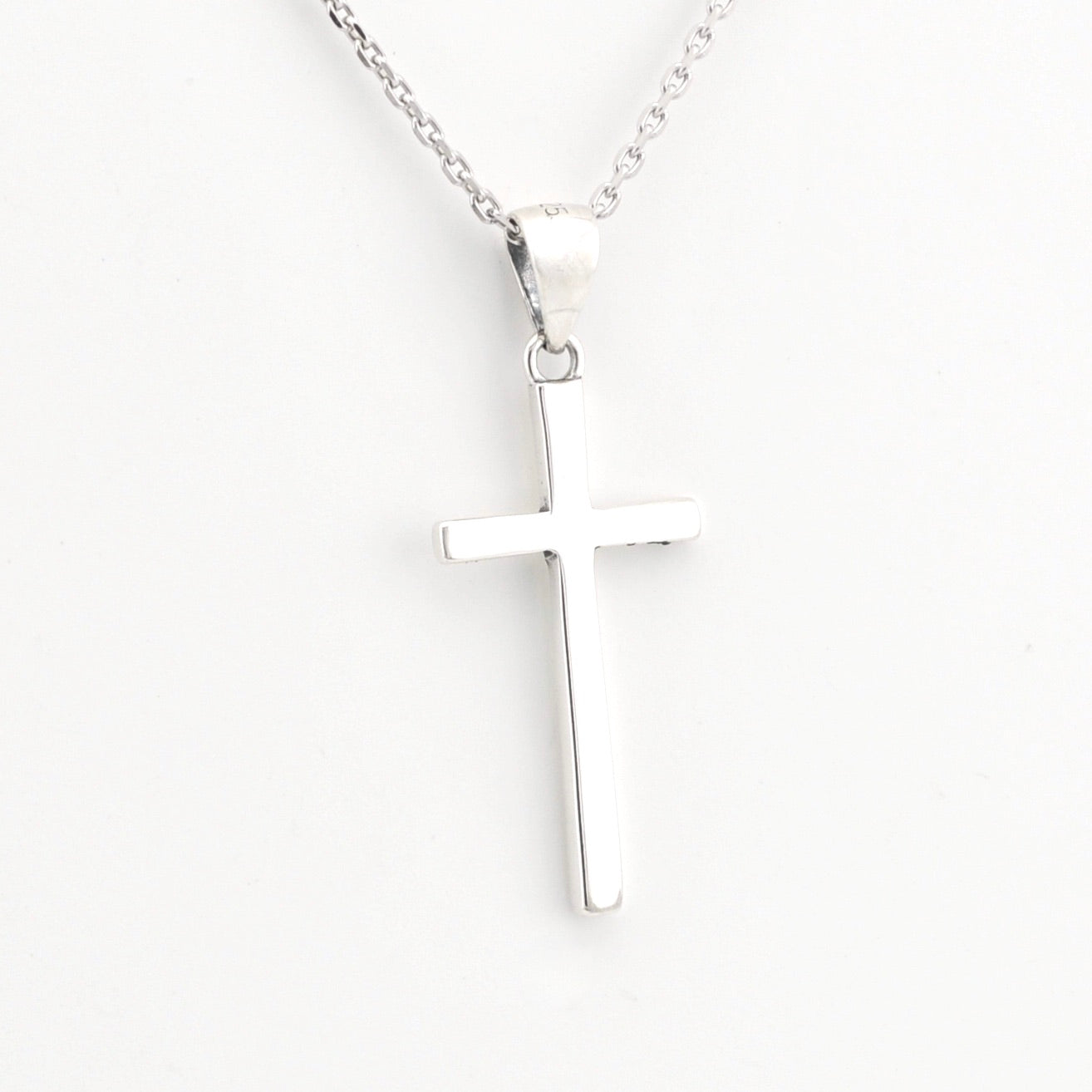 Silver cross pendant on a chain against a white background