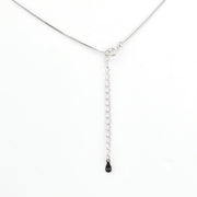 Silver chain necklace with a small black pendant on a white background