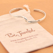 Silver bracelet on a 'Be Jeweled' branded pouch with a beige background