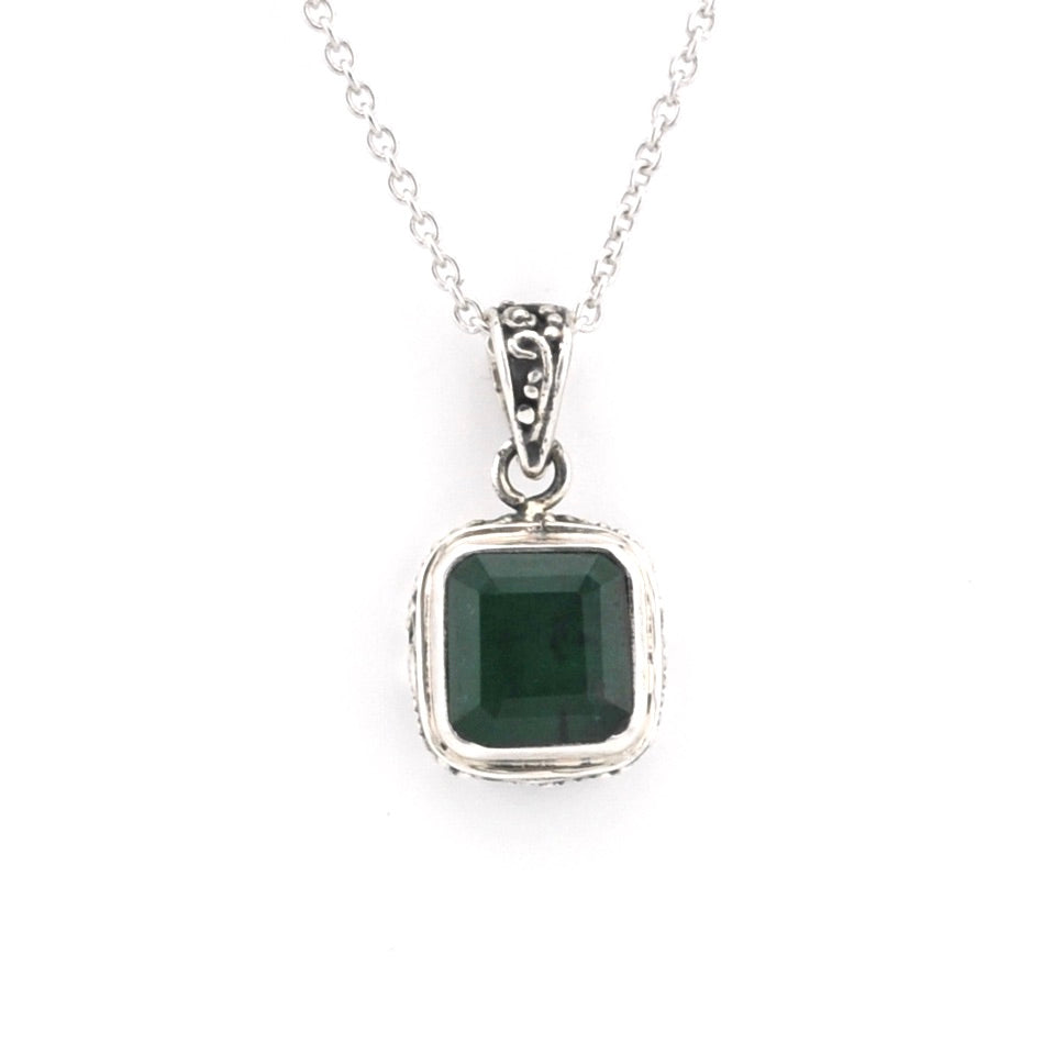 Silver pendant with a green gemstone on a white background