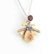 Gold and silver pendant with a red gemstone on a white background