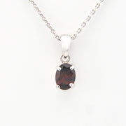 Silver pendant with a dark gemstone on a white background