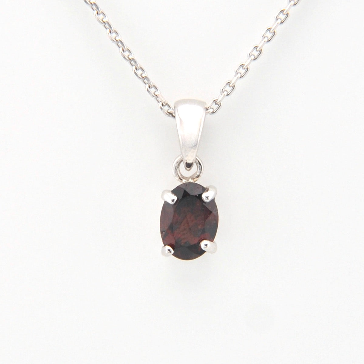 Silver pendant with a dark gemstone on a white background