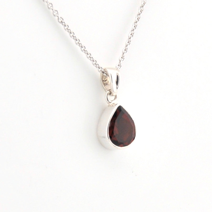 Teardrop-shaped pendant with a red gemstone on a white background