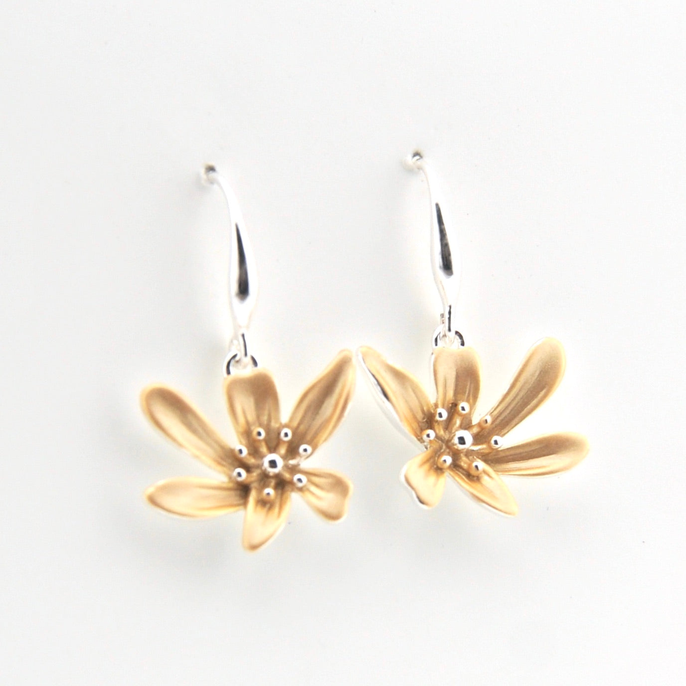 Gold flower-shaped earrings on a white background