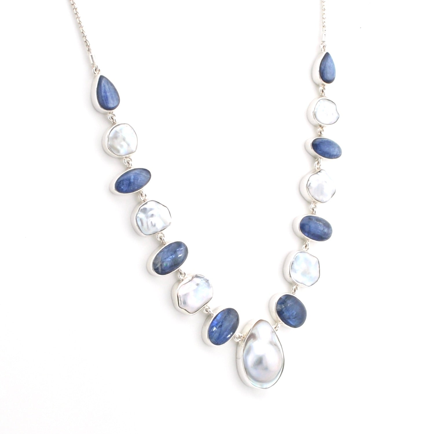A silver-toned beaded necklace featuring alternating polished blue oval-shaped stones and irregular white keshi pearls, displayed on a clean white background.