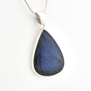 Teardrop-shaped blue pendant on a silver chain against a white background