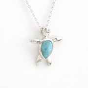 Silver turtle pendant with a blue stone on a white background