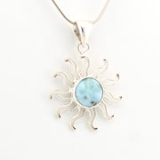 Sun-shaped pendant with a central gemstone on a white background