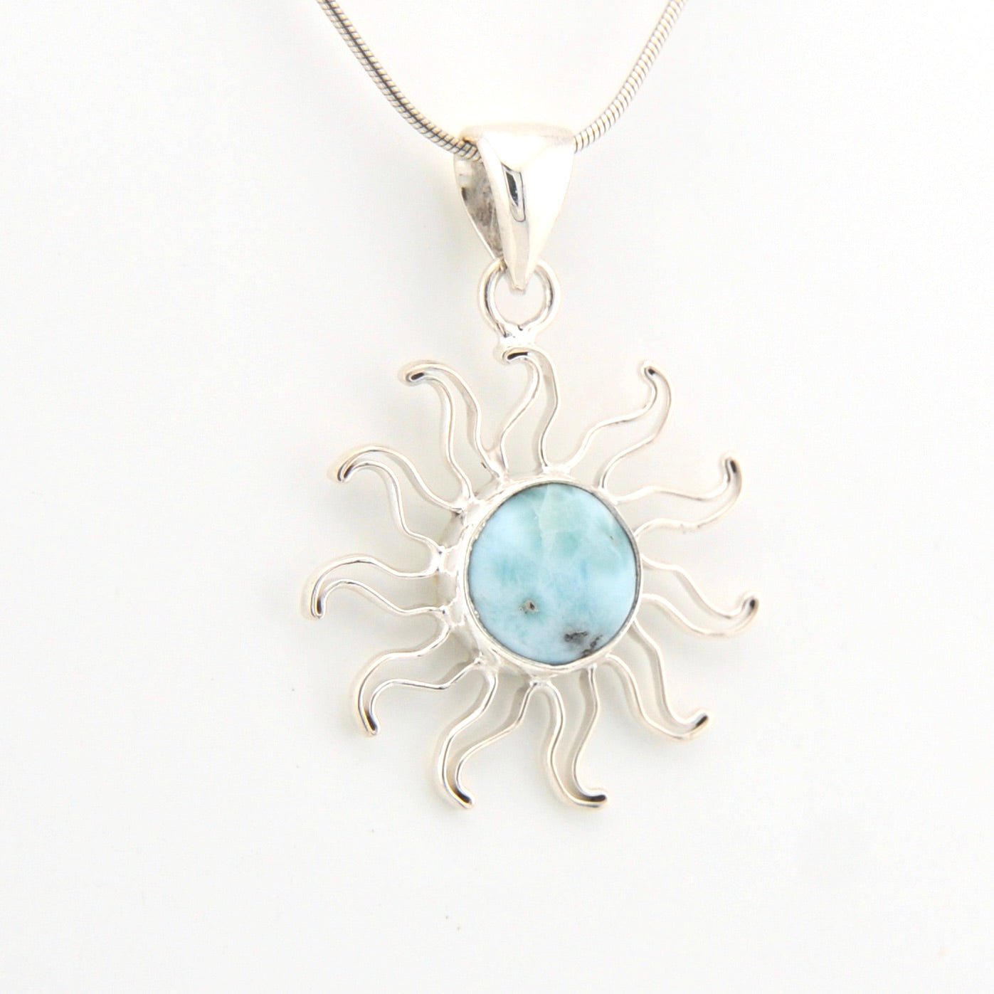 Sun-shaped pendant with a central gemstone on a white background