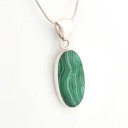 Green malachite pendant on a silver chain against a white background