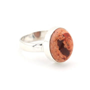 Ring with a red stone and silver band on a white background