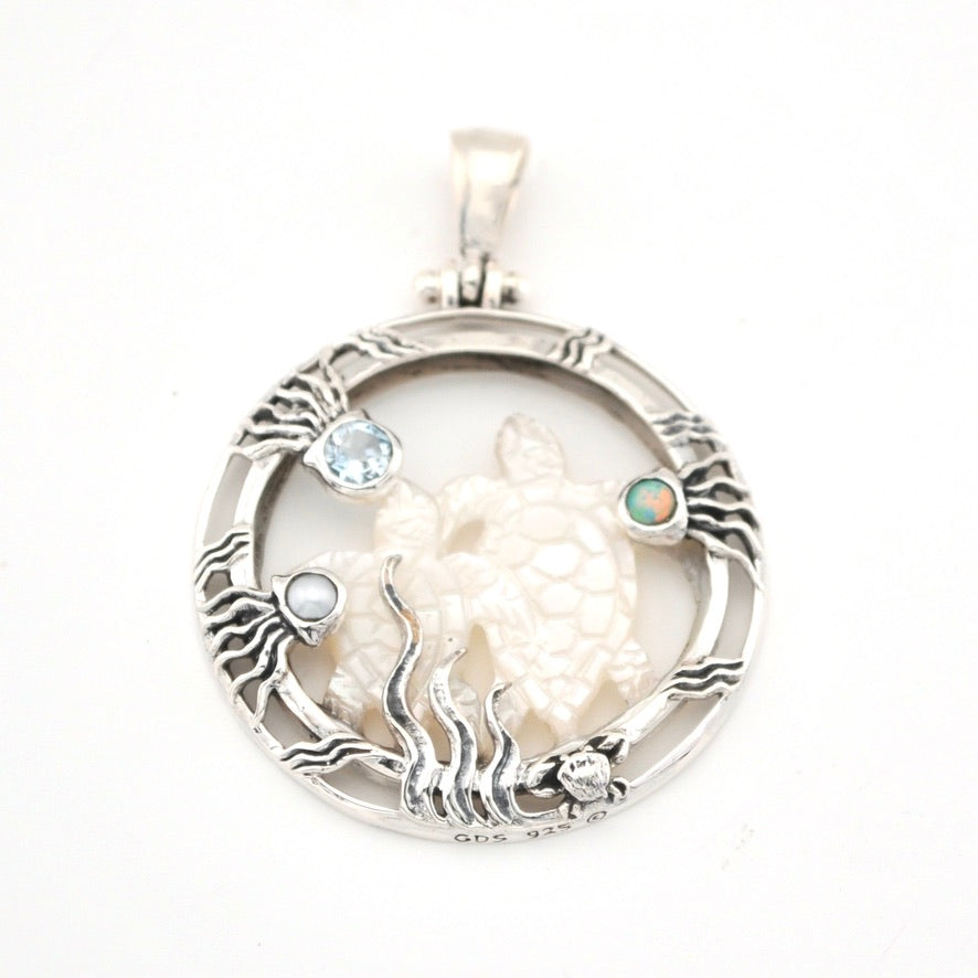 Silver pendant with a turtle design and gemstones on a white background