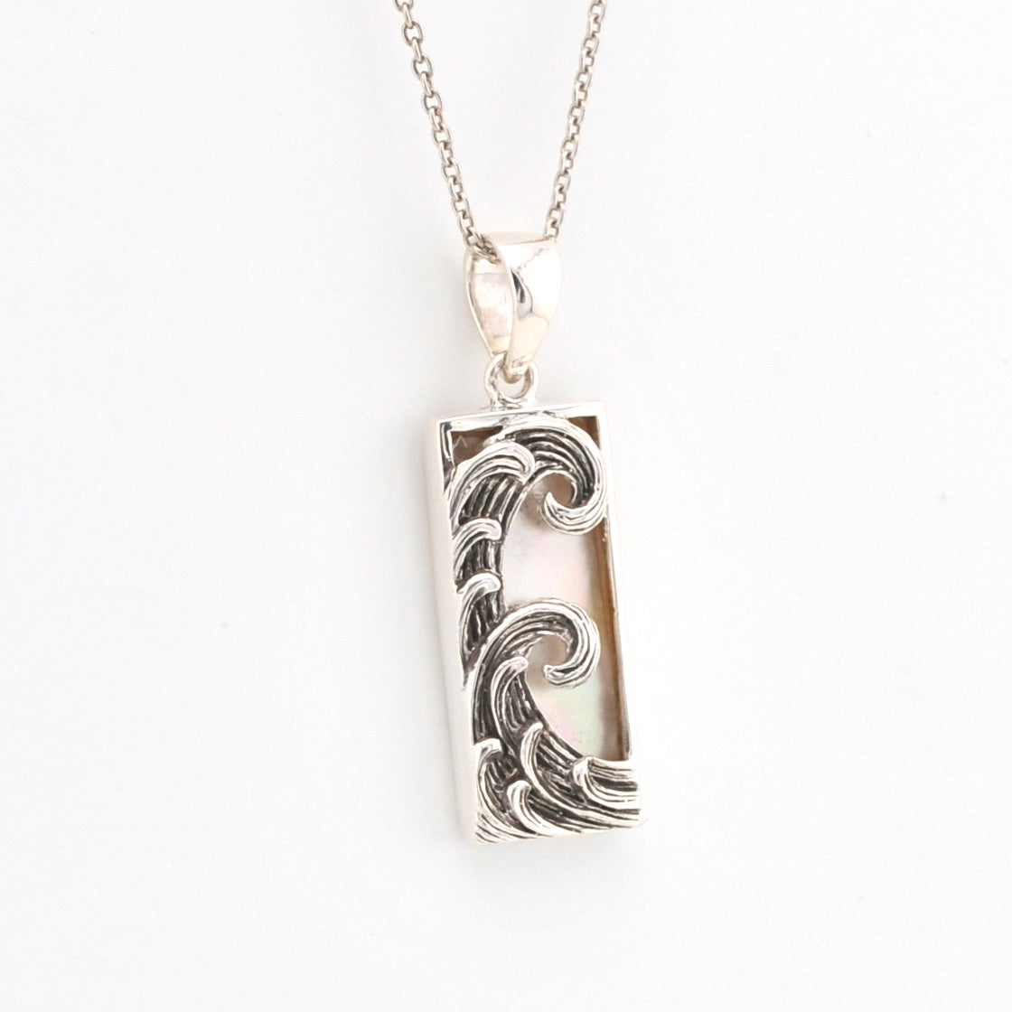 Silver wave pendant necklace on a white background