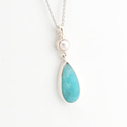 Necklace with a teardrop-shaped blue pendant and pearl on a white background