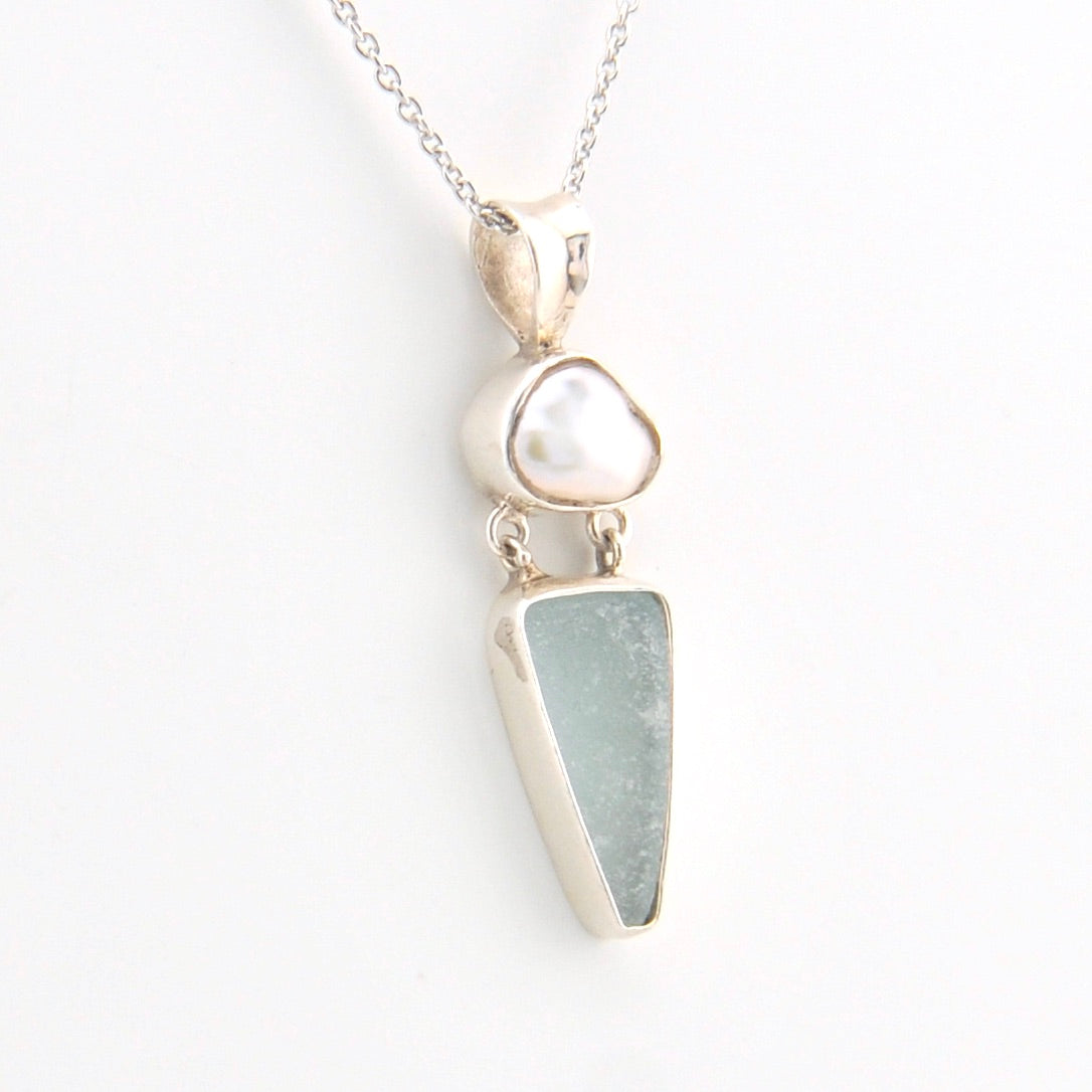 Necklace with a pendant featuring a  pearl and sea glass on a white background
