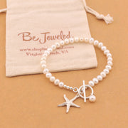 Pearl bracelet with starfish charm on a beige background with 'Be Jeweled' pouch.