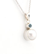 Necklace with a pearl pendant and blue gemstone on a white background